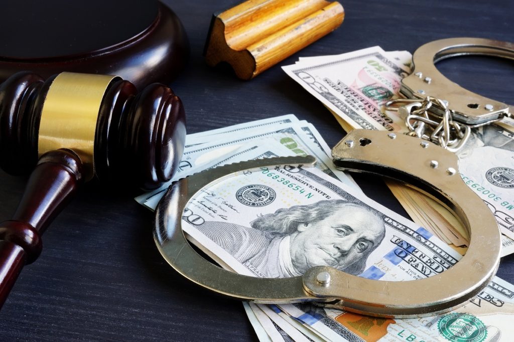 Handcuffs and gavel on stack of bills
