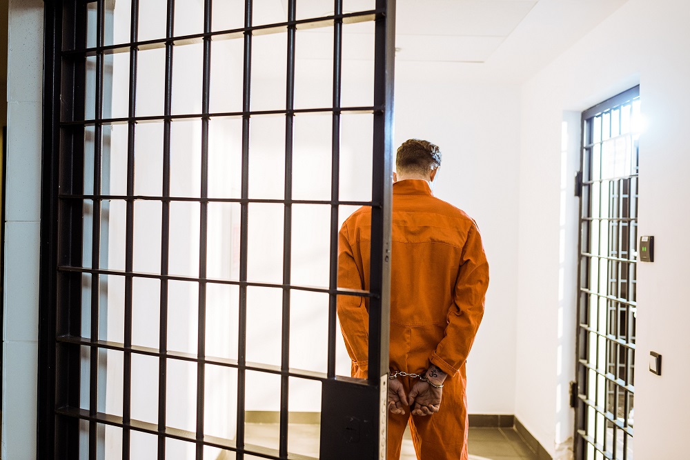 Back of Person in Orange Jail Suit and Handcuffed and in Jail